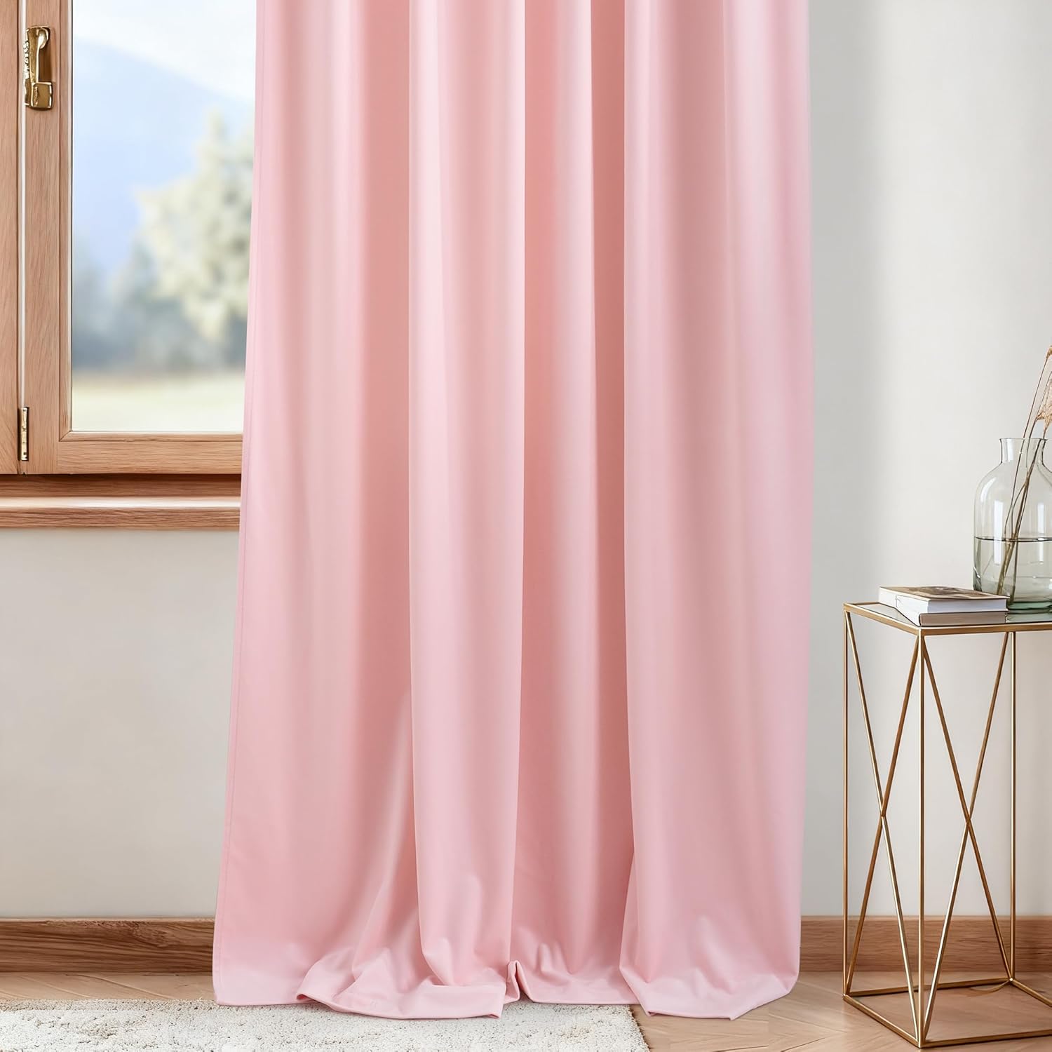 Light pink solid curtain panel with grommet top, hanging by a wooden window and gold side table.
