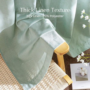 Light sage green thick linen blend curtain draped over a natural wood chair with a woven seat.