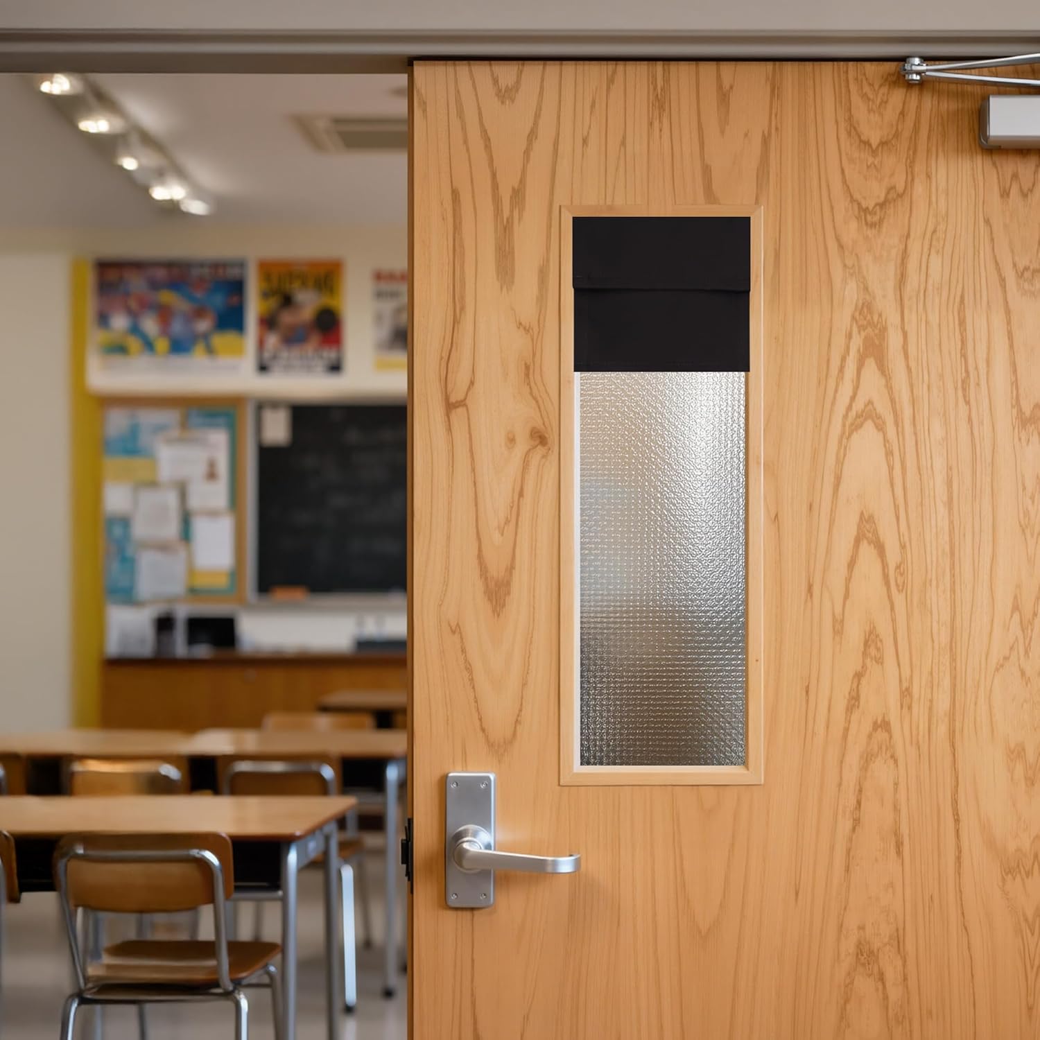 Light wood classroom door with frosted window, black privacy shade, and silver handle.