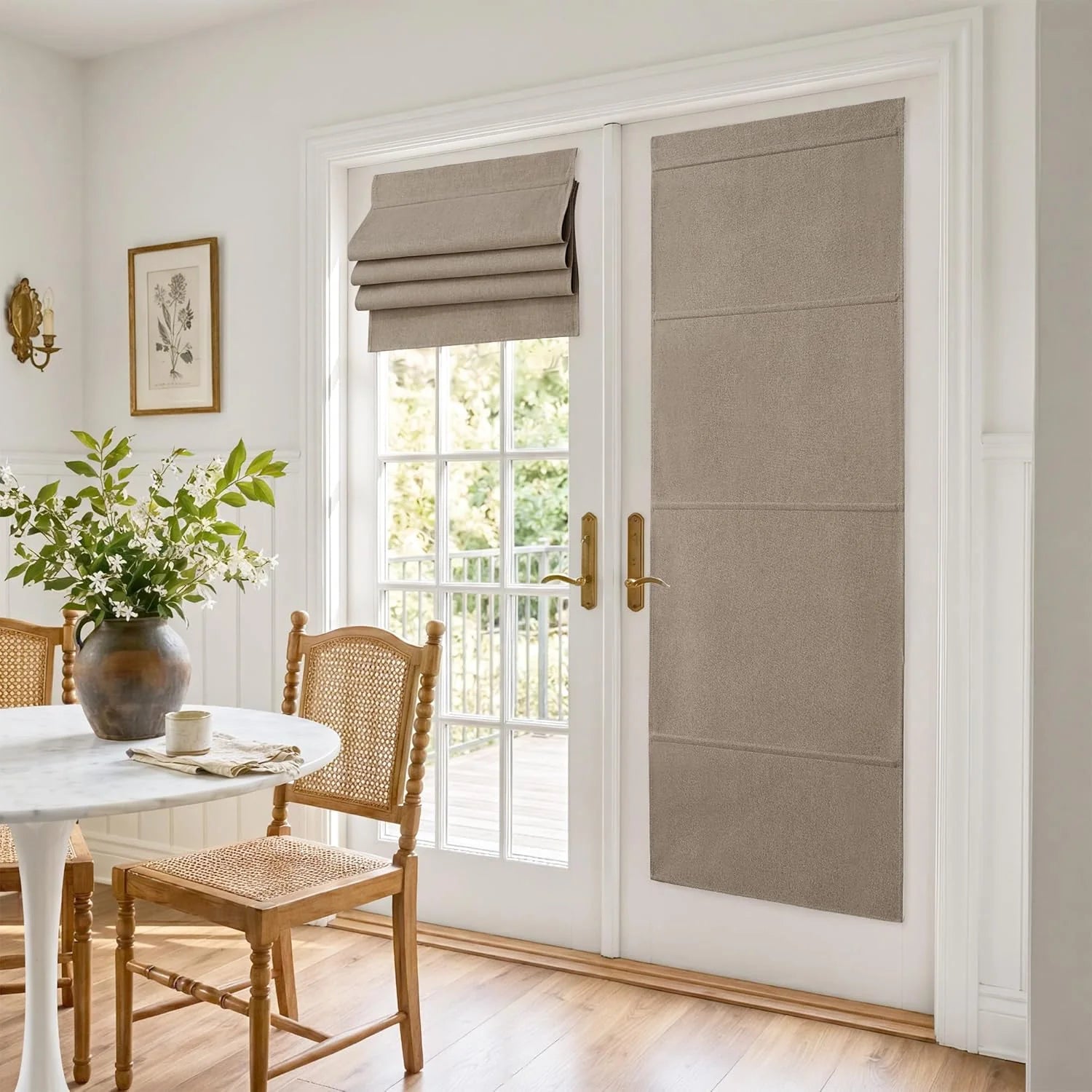 Neutral Roman blinds on white French doors in a sunny dining room with marble table and cane chairs.
