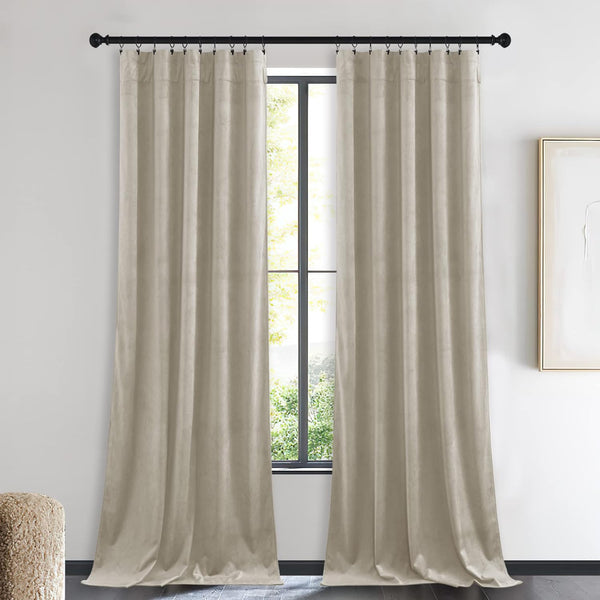 A pair of long beige velvet curtains with clip rings hanging on a black rod in a modern room.