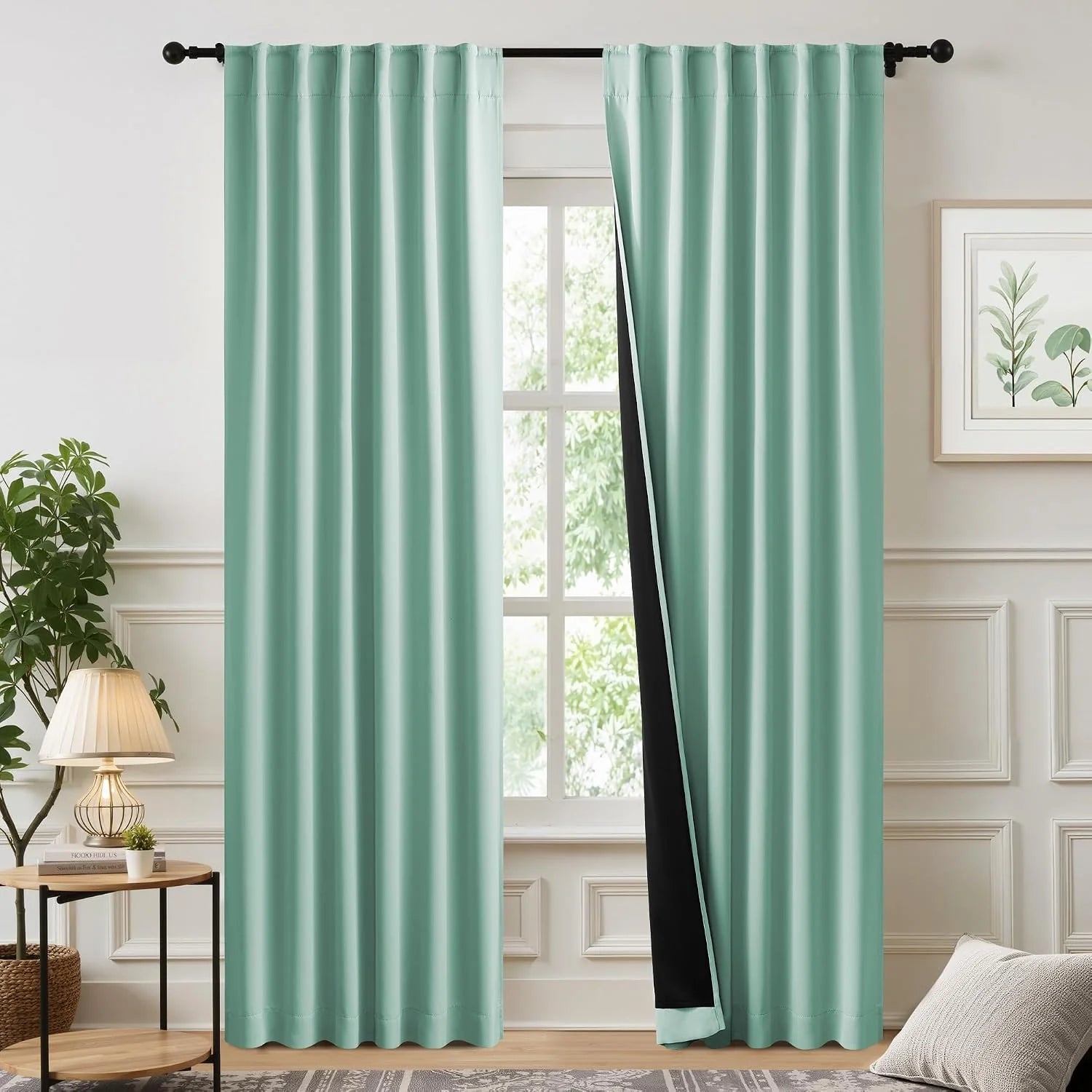 Mint green blackout curtains with black lining on a rod in a bright living room window