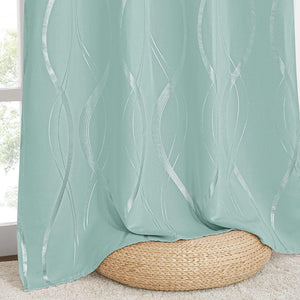 Mint green window curtain with a modern vertical silver foil wavy pattern, draped over a natural woven pouf on a carpet.