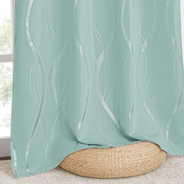 Mint green window curtain with a modern vertical silver foil wavy pattern, draped over a natural woven pouf on a carpet.