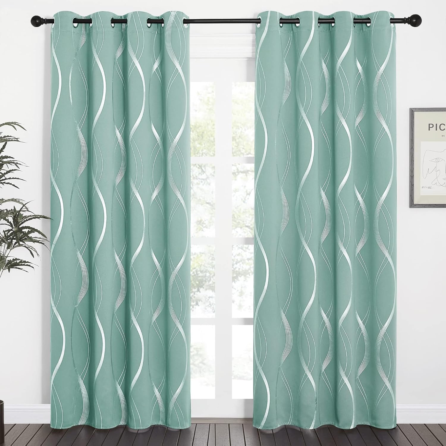 Mint green blackout curtains with wavy silver pattern and black grommet tops hanging in a bright room.