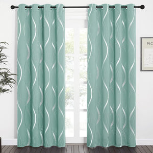 Mint green blackout curtains with wavy silver pattern and black grommet tops hanging in a bright room.