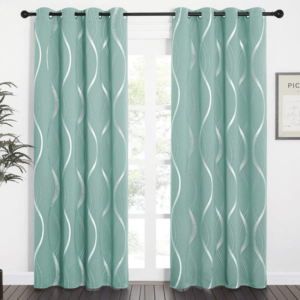 Mint green blackout curtains with wavy silver pattern and black grommet tops hanging in a bright room.