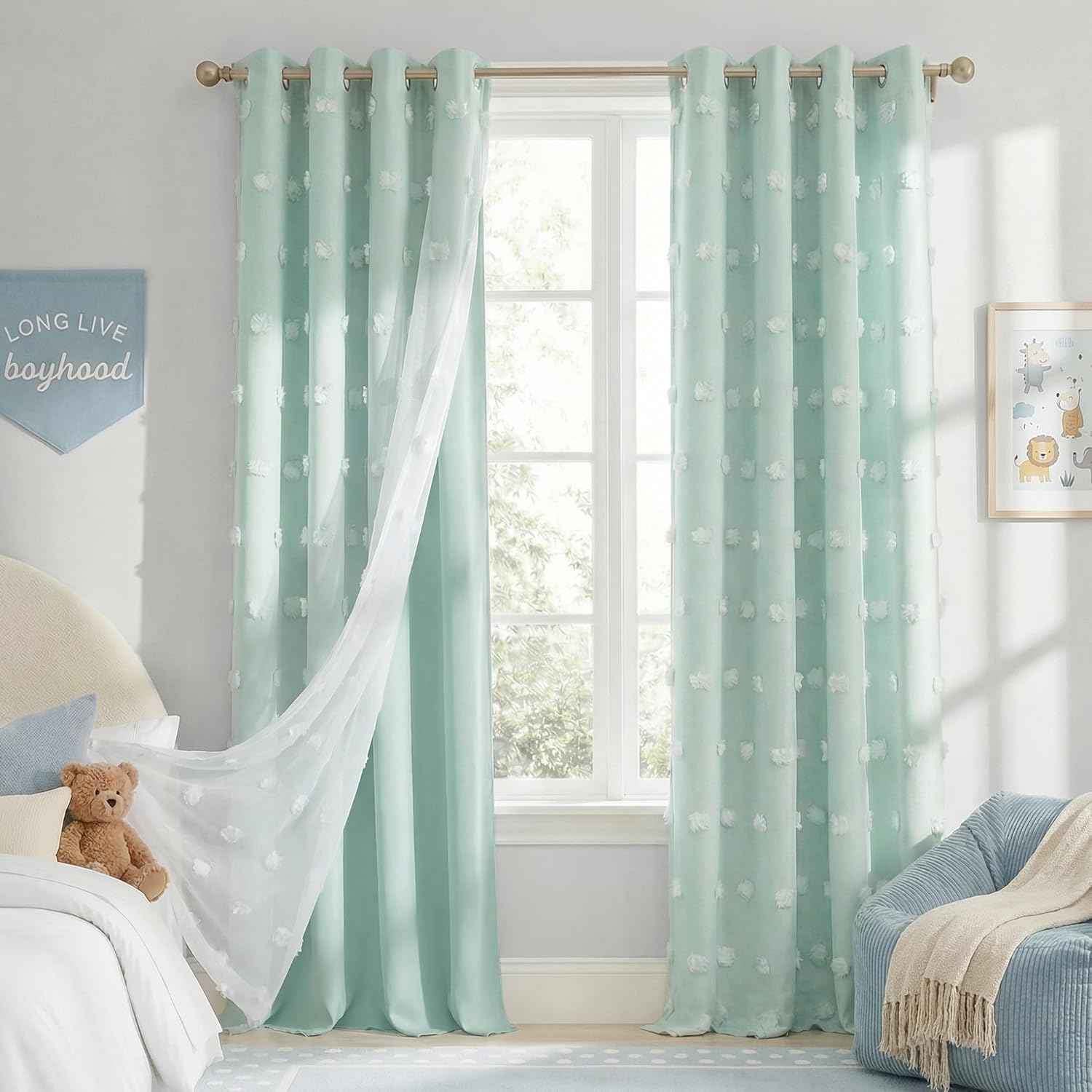 Mint green grommet curtains with white tufted pompoms and sheer inner panel in a child's bedroom.