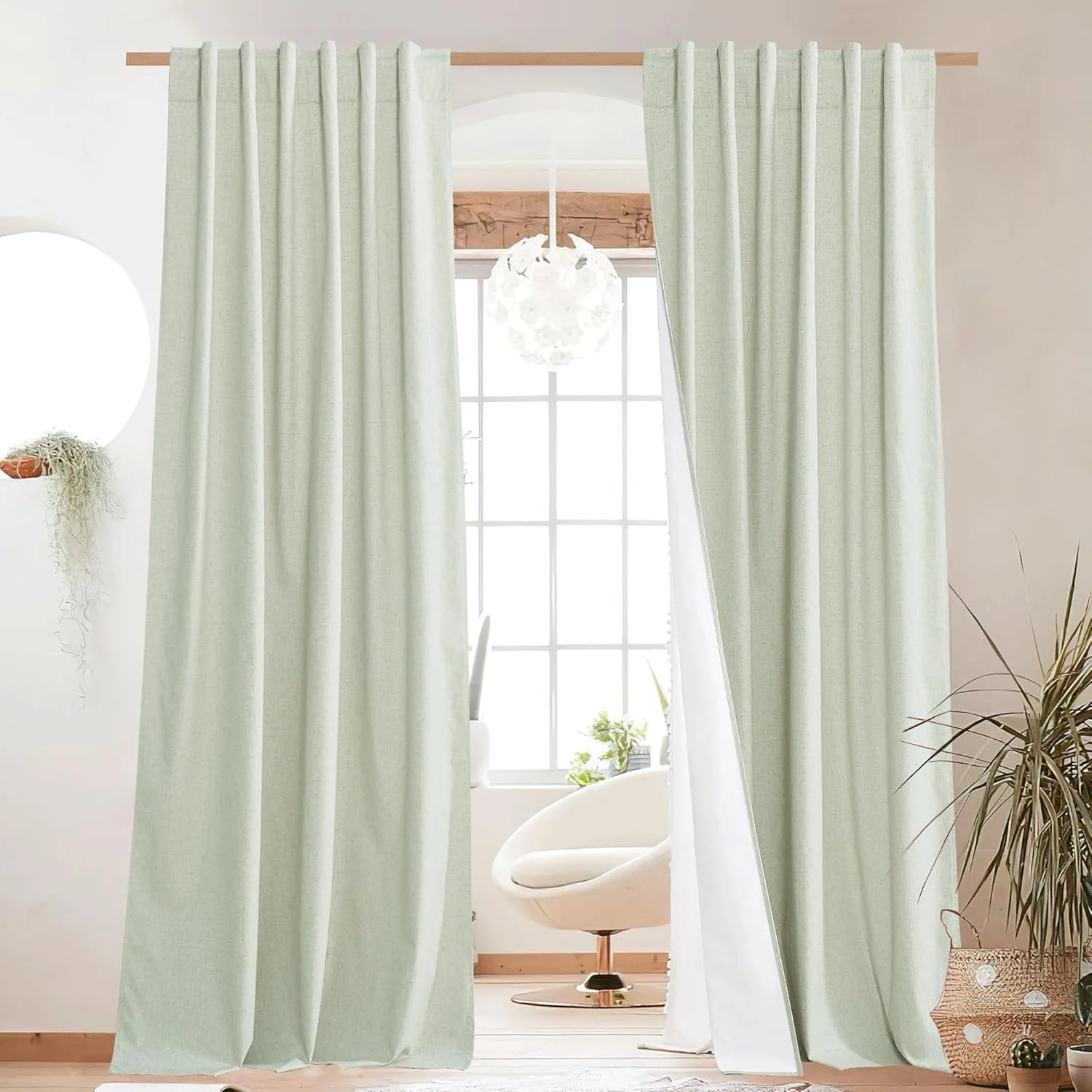 Soft mint linen-look curtains hanging on a wooden rod in a bright modern room