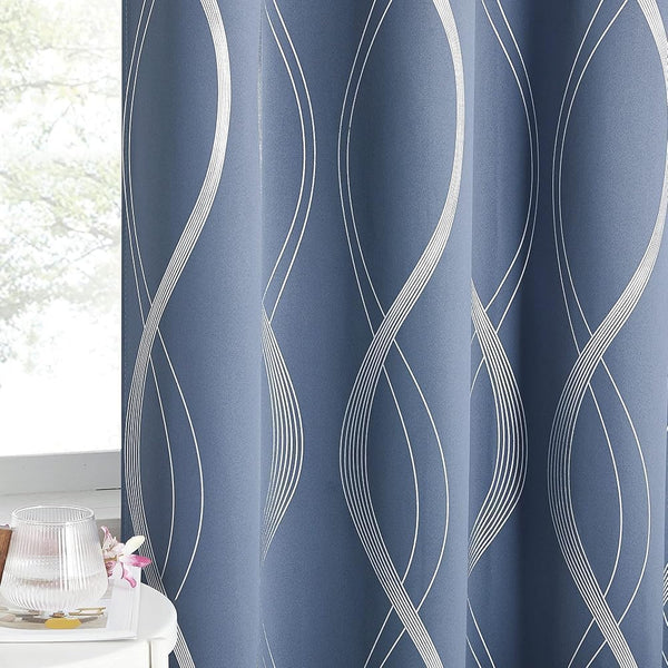 Elegant dusty blue curtain with modern white wavy abstract pattern hanging by a sunlit window.
