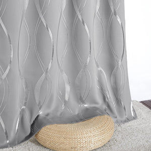Elegant gray blackout curtain with shimmering silver wavy line pattern draped over a woven pouf.
