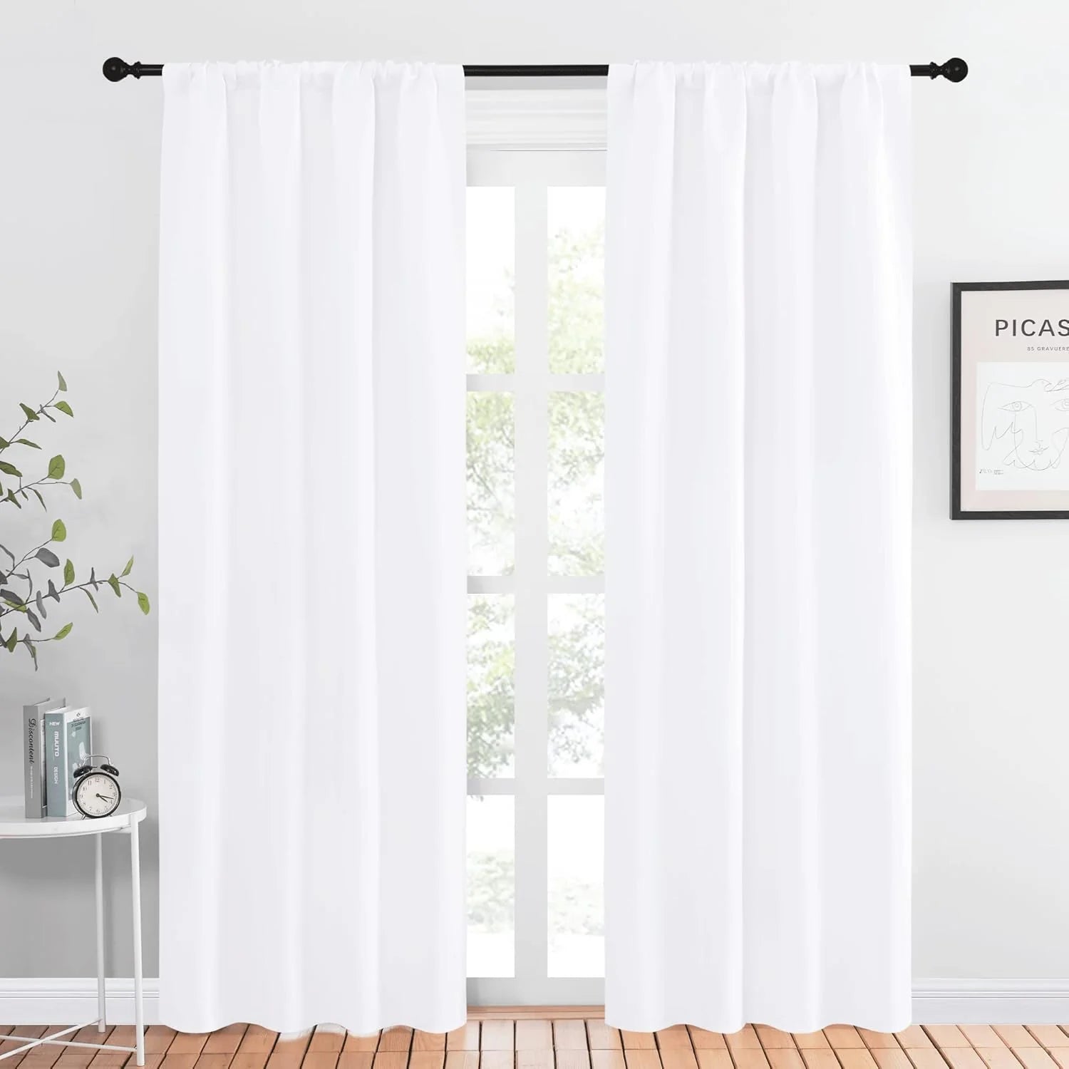 Bright white rod pocket curtains on a black rod in a modern, sunlit room with wooden floor.