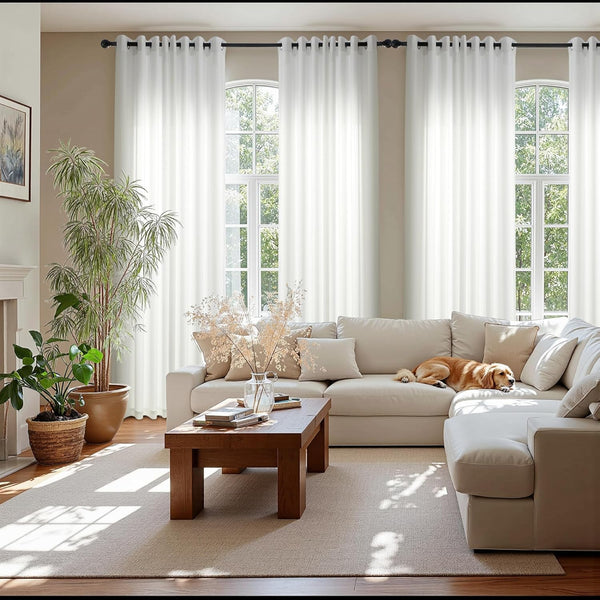 White sheer grommet curtains hanging over arched windows, diffusing natural light in a modern living room.