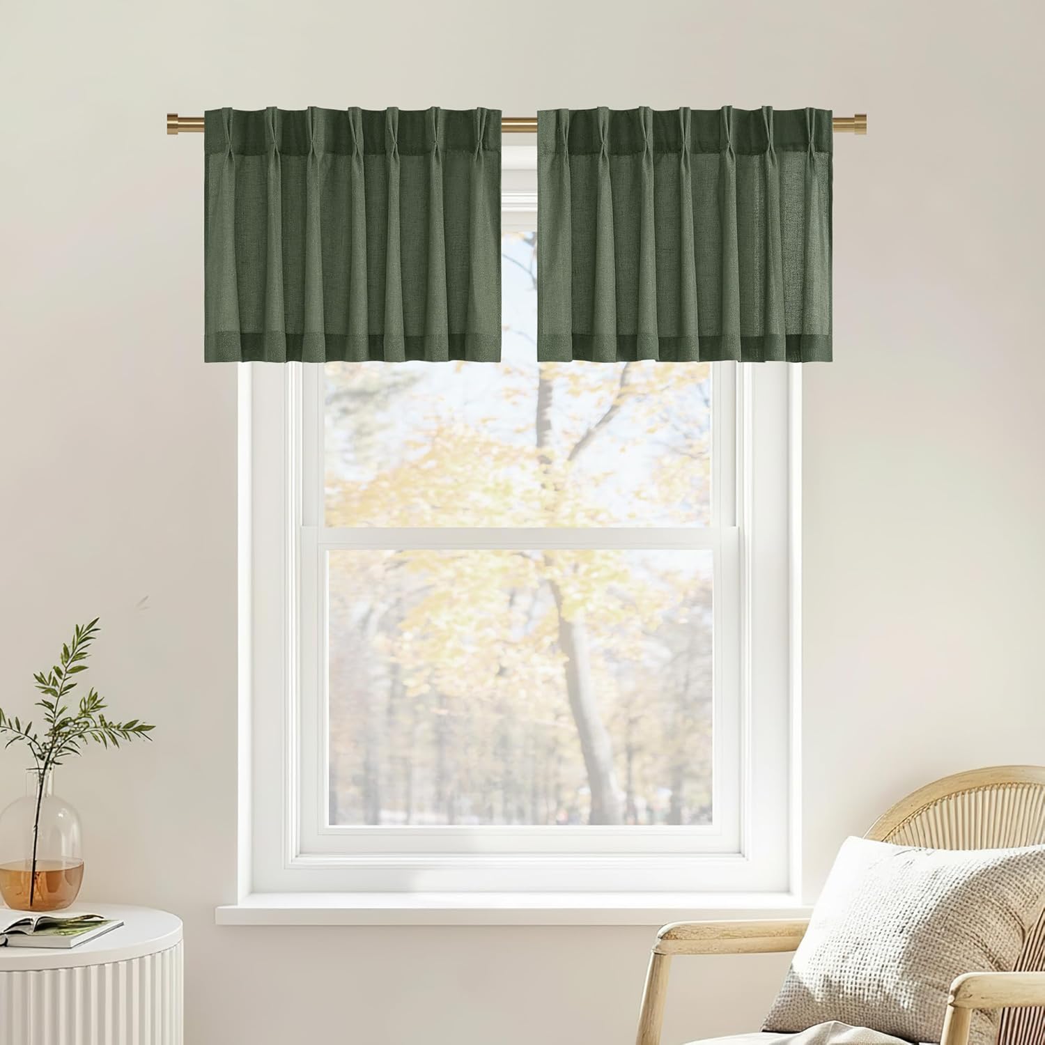Pair of moss green textured pinch pleat cafe curtains hanging on a brass rod over a window.
