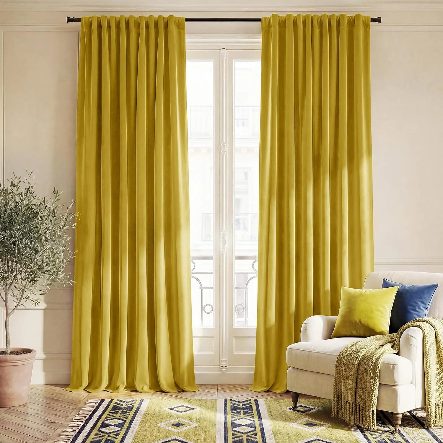 Mustard yellow velvet curtains hanging in a bright living room beside a cream armchair