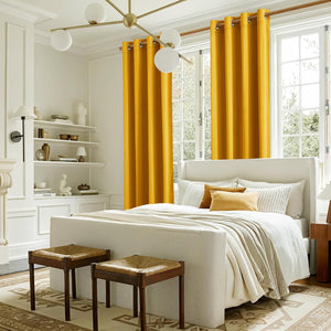 Rich mustard yellow grommet top curtains beautifully frame a large window in a bright bedroom setting.