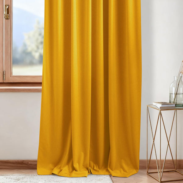 Rich mustard yellow velvet curtain hanging softly next to a wooden window. It adds warmth and texture.