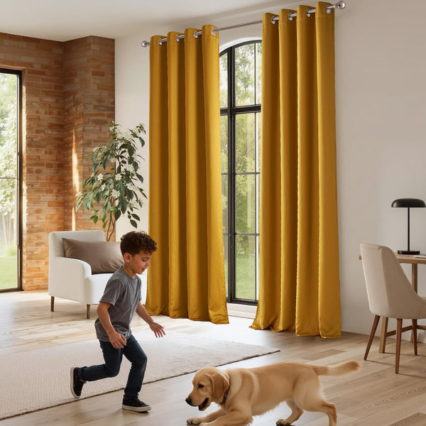 Rich mustard yellow velvet grommet top curtains draped on a silver rod in a bright, modern living room.