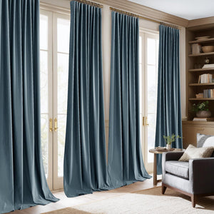 Luxurious muted blue velvet pinch pleat drapes on gold rods, framing bright glass doors in a sunlit living room.