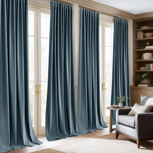 Luxurious muted blue velvet pinch pleat drapes on gold rods, framing bright glass doors in a sunlit living room.