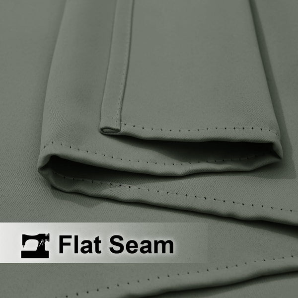 Close-up of muted grey fabric with a folded edge showing a neatly executed flat seam and fine, even stitching.