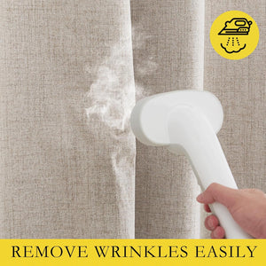 A hand uses a white garment steamer on natural beige linen curtains, removing wrinkles easily.