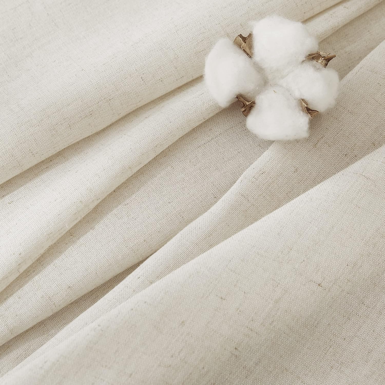Close-up of natural cream woven cotton linen blend fabric with subtle texture and a white cotton boll.