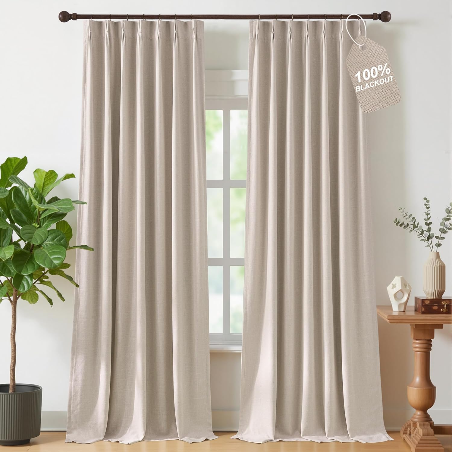 Pair of natural linen textured 100% blackout pinch pleat curtains on a dark rod in a bright room.