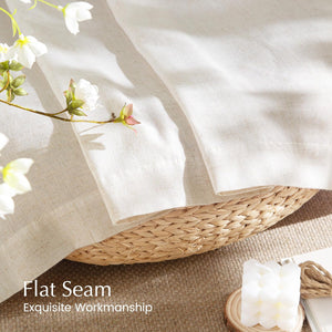 Close-up of natural linen-blend fabric in light beige, showcasing exquisite flat seam stitching draped over a woven basket.