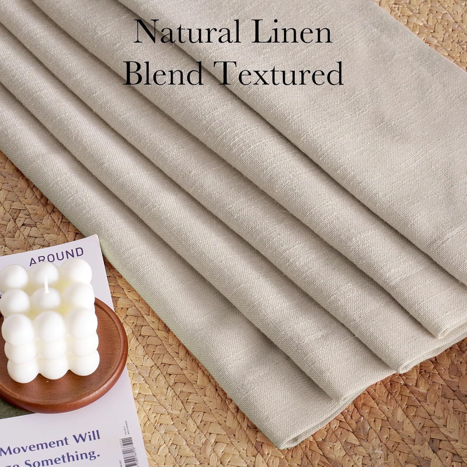 Natural linen blend textured fabric in light beige, folded neatly on a woven mat, highlighting its weave.