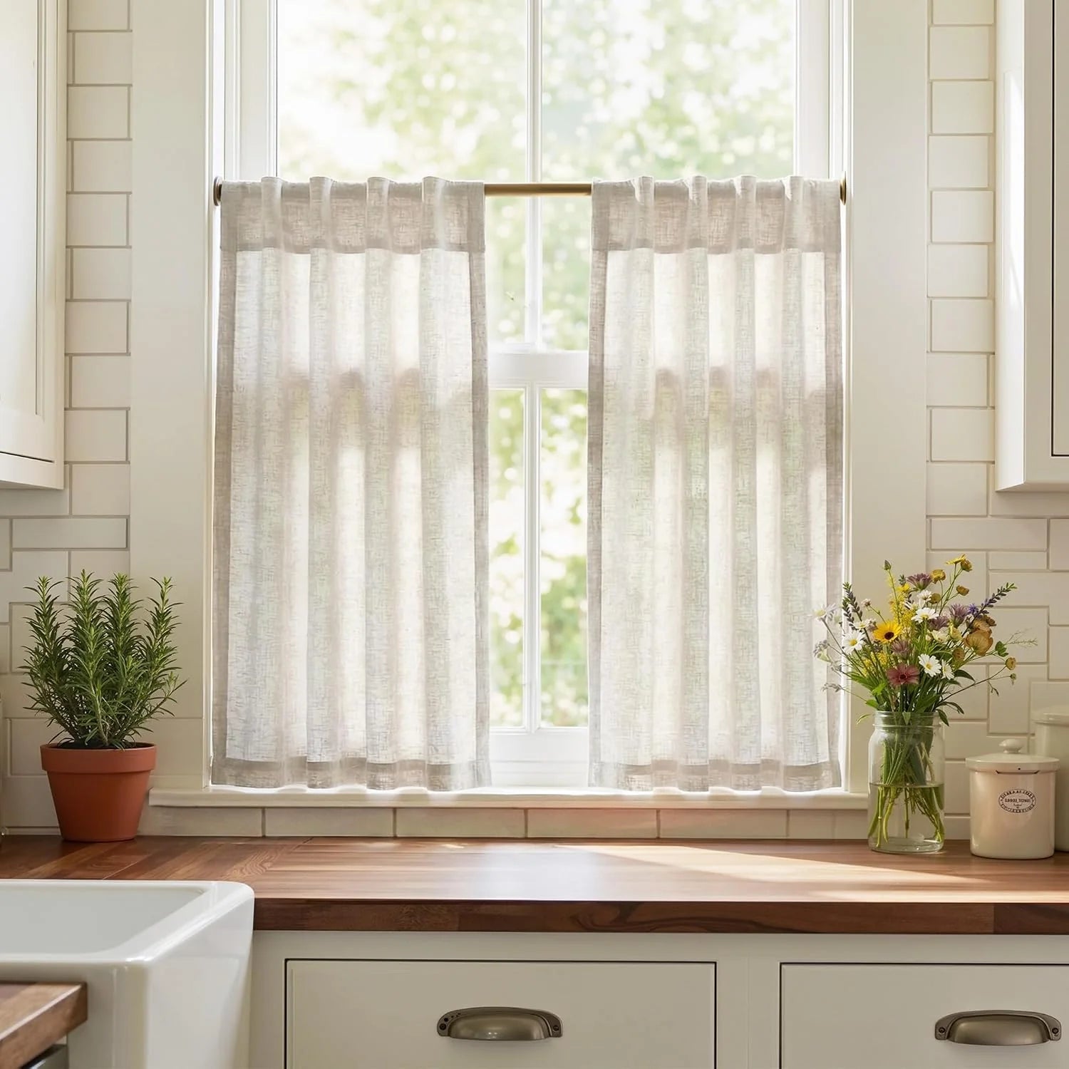 Light natural linen cafe curtains on a brass rod in a bright farmhouse kitchen window.