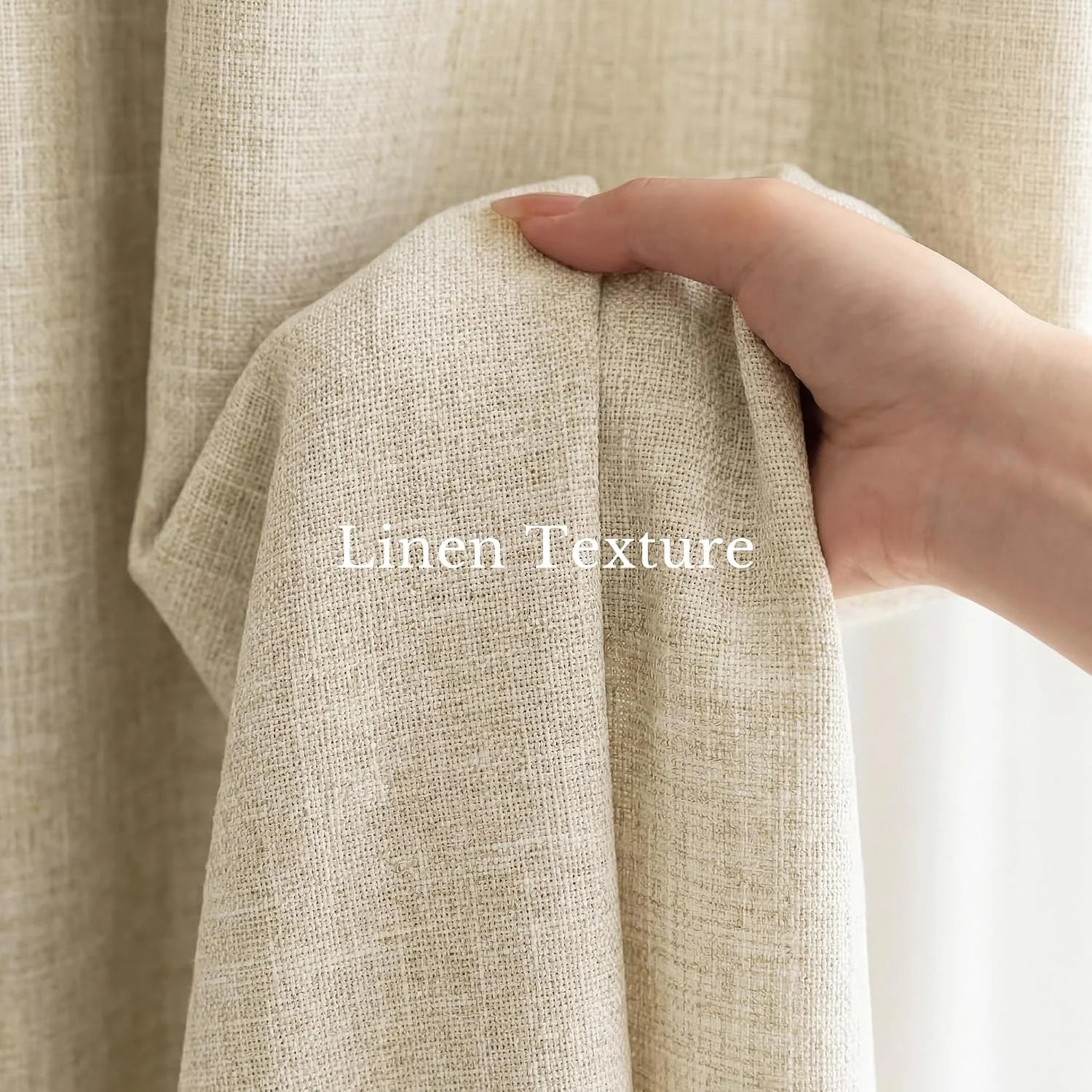 A hand gently holds up natural beige linen fabric, showcasing its woven texture and soft drape.