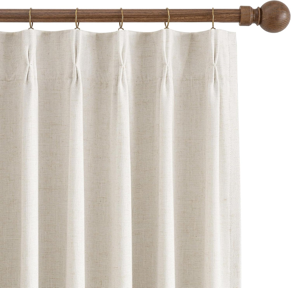 Natural linen off-white pinch pleat curtain panel hanging from a dark wood rod with brass rings.