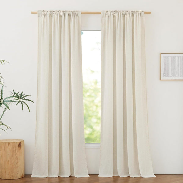 Two light beige linen rod pocket curtain panels hanging on a wood rod, filtering sunlight.