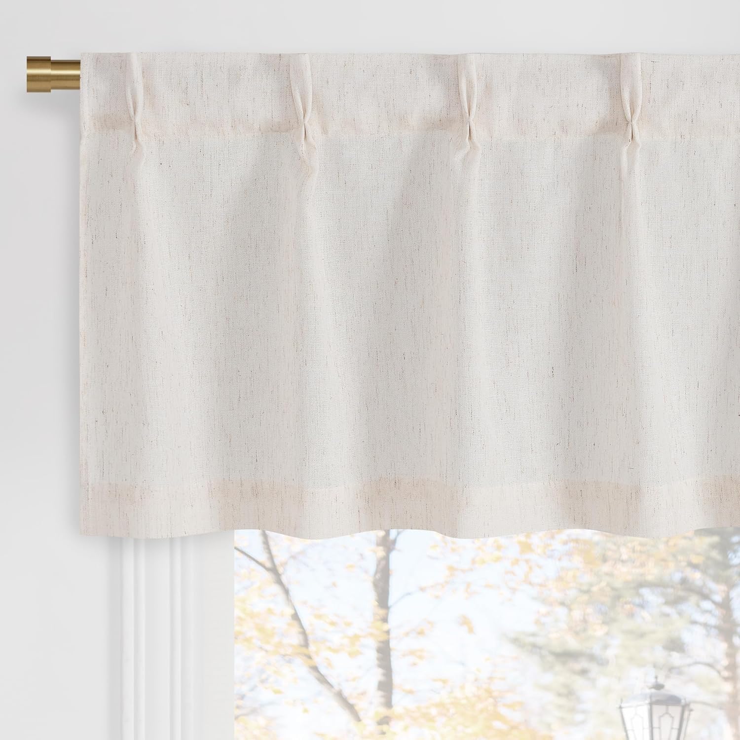Natural off-white linen rod-pocket valance with tailored pleats on a brass rod over a window.