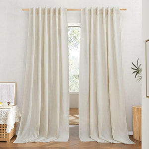 A pair of natural linen tab top curtains with visible texture, hanging on a wooden rod over a window.