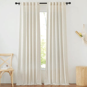 Pair of natural linen-textured back tab curtains on a black rod in a bright room.