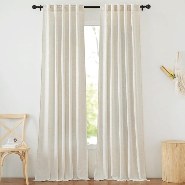 Pair of natural linen-textured back tab curtains on a black rod in a bright room.