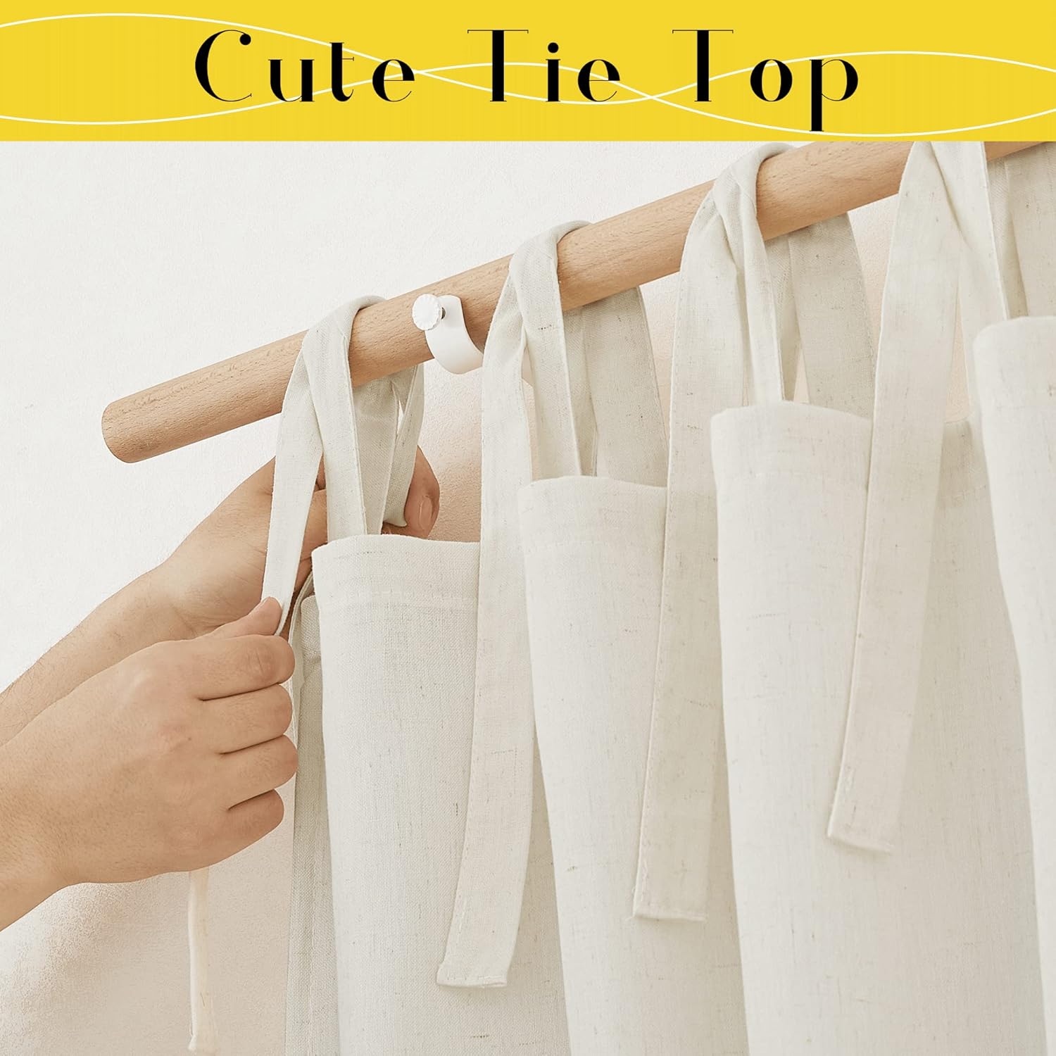 Person's hands adjusting a natural beige textured linen tie-top curtain hanging on a light wooden rod.