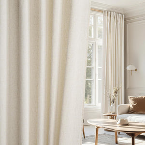 Close-up of a natural textured cream linen blend curtain panel with soft pleats in a bright modern living room.