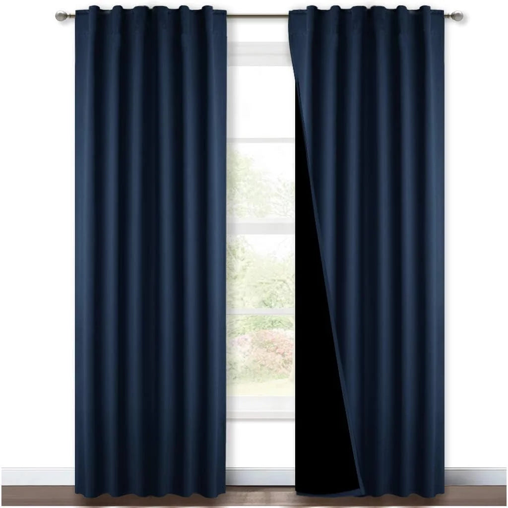 Dark navy blackout curtains with rod pocket pleats hanging over a bright window