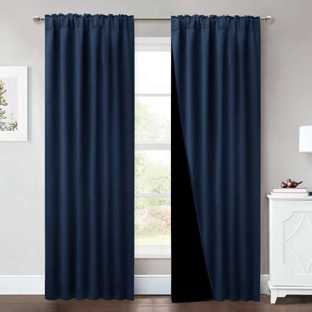 Navy blue blackout curtains hanging on a silver rod in a bright modern room