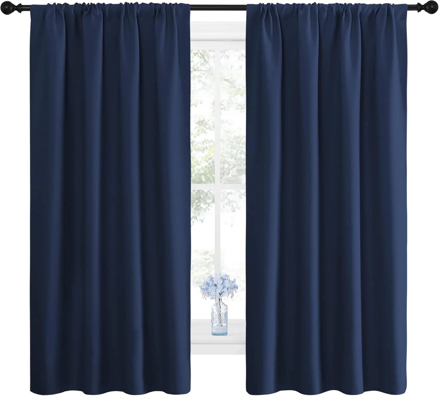 Navy blue blackout curtains with rod pocket top on black rod, in a room with a window and small vase.