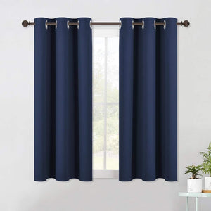 Two navy blue blackout curtains with silver grommet tops hanging from a dark bronze rod over a window.