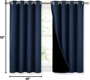 Pair of navy blue blackout curtains with silver grommet tops hanging on a curtain rod over a window