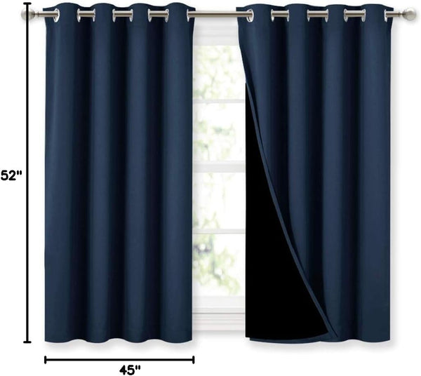 Pair of navy blue blackout curtains with silver grommet tops hanging on a curtain rod over a window
