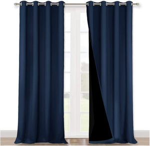 Two navy blue blackout curtains with silver grommet tops hanging on a silver rod. One panel is partially open, revealing the black lining.