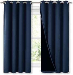 Navy blue blackout curtains with silver grommet tops on a window, revealing dark lining.