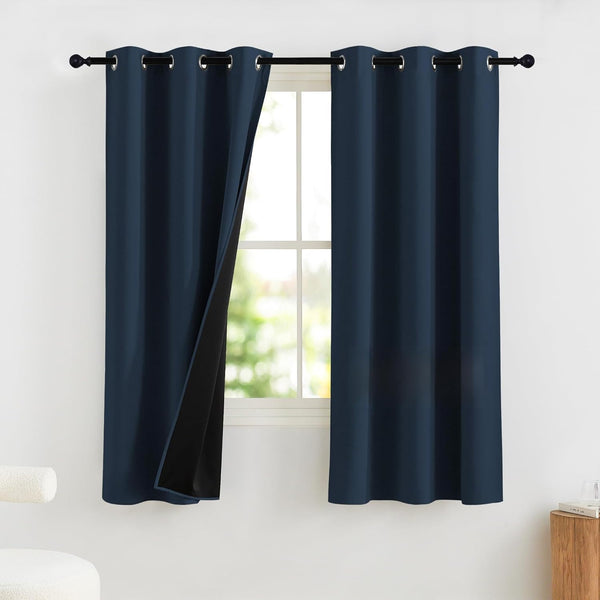 Navy blue blackout curtains with silver grommet tops. One panel reveals dark, light-blocking lining.