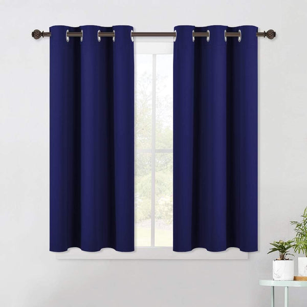 Two navy blue blackout curtain panels with silver grommets hang on a brown rod over a window.
